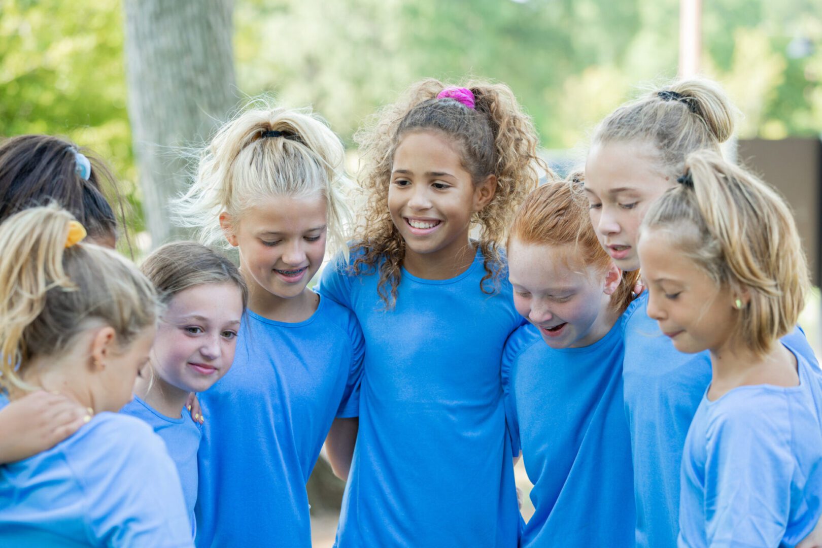 Girls in blue shirts huddling together.
