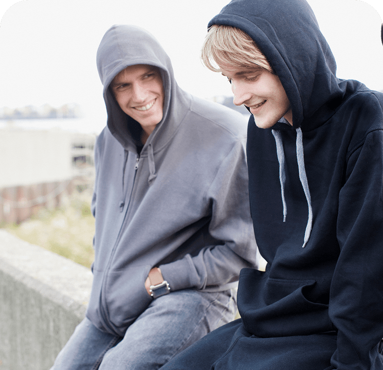 Two people sitting, wearing hooded sweatshirts.