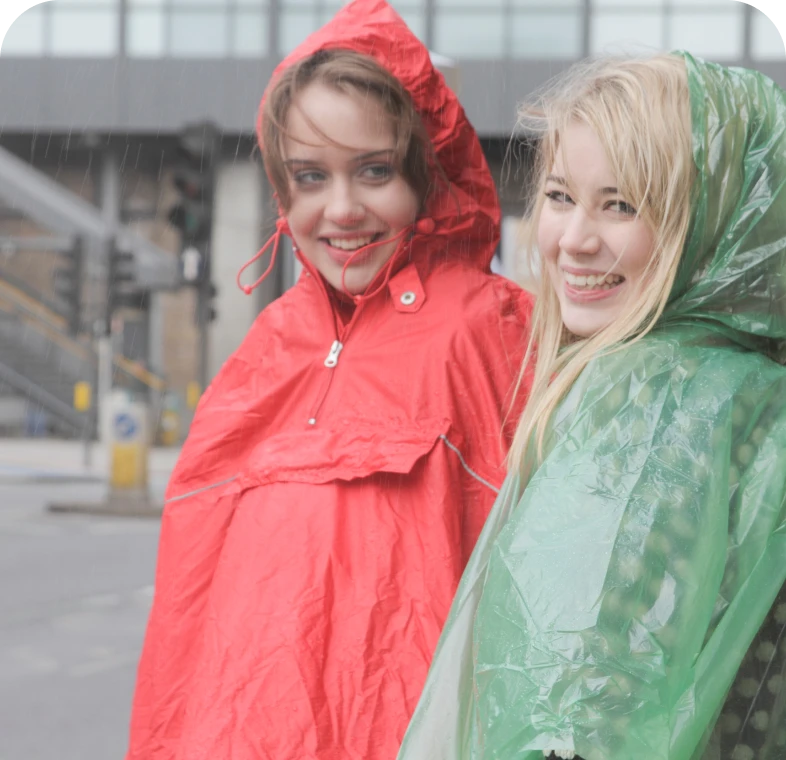 Two women smiling in rain ponchos.