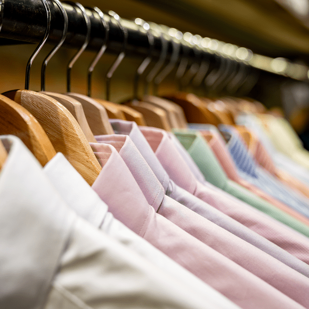 Assorted dress shirts on wooden hangers.